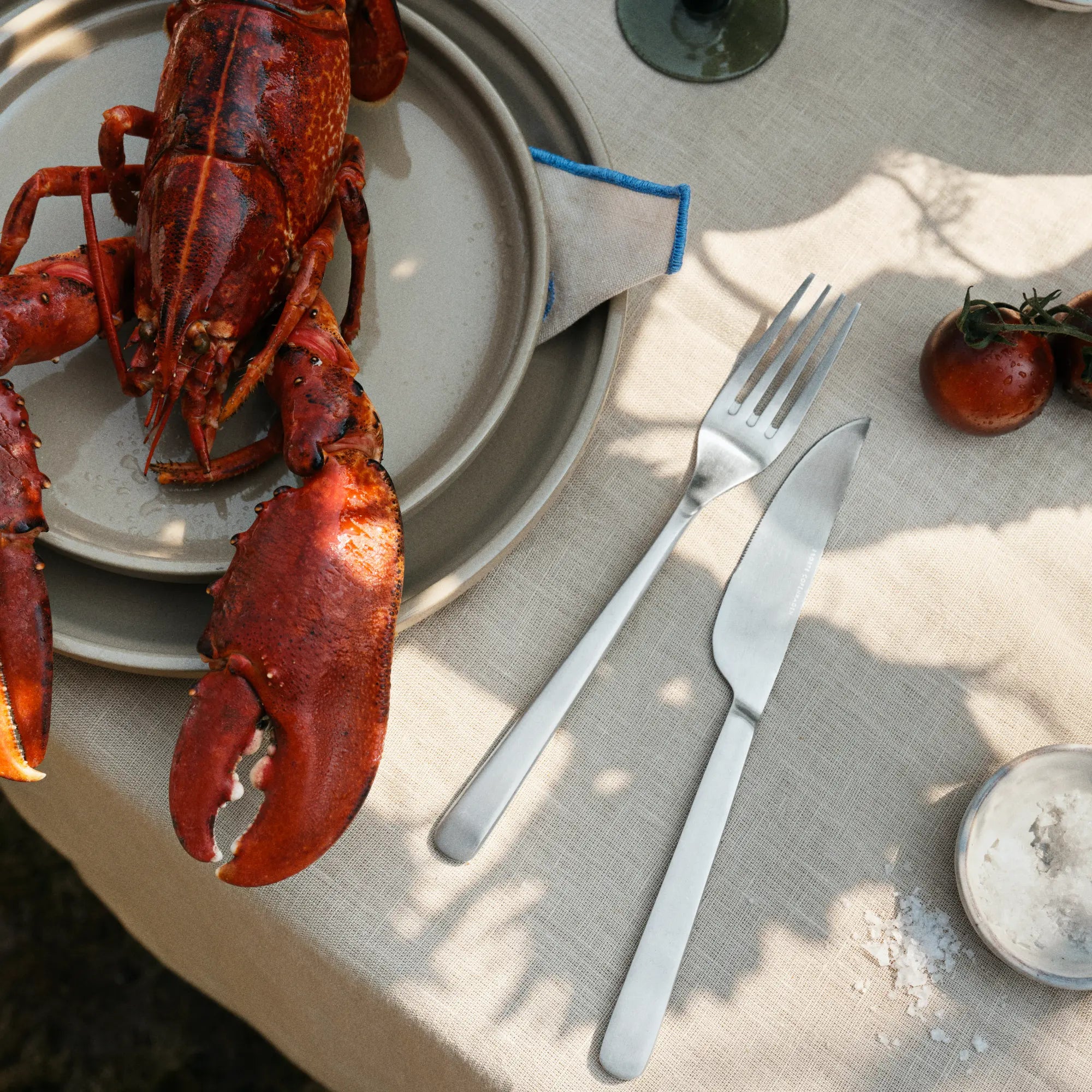  A woman's hand holding the Nordic Bistro Cutlery Set with a bowl of salad in the background 